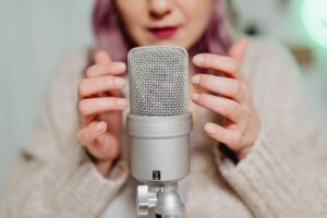 Senior woman speaking into professional microphone in home recording setup