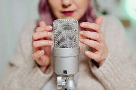 Senior woman speaking into professional microphone in home recording setup