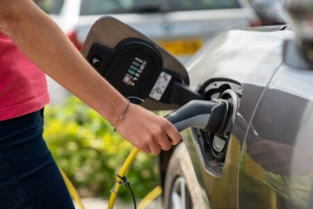 Electric vehicle plugged into charging station at automotive service facility