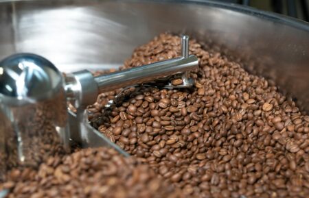 Independent Coffee Roasters Compete With Starbucks Through Corporate Partnerships Coffee beans being roasted in industrial roasting machine at independent coffee roastery