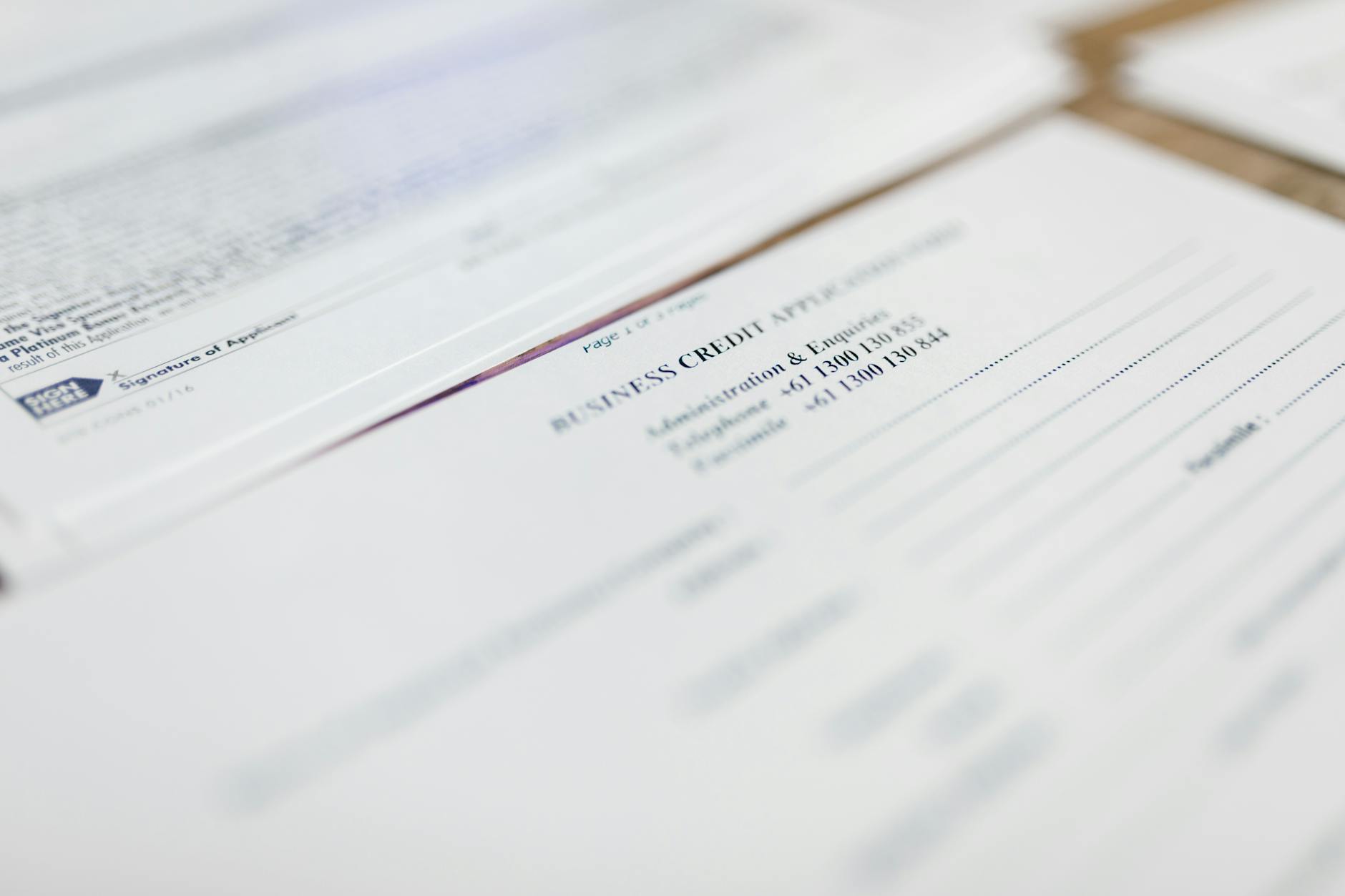 Stack of business permits and regulatory documents on desk with calculator