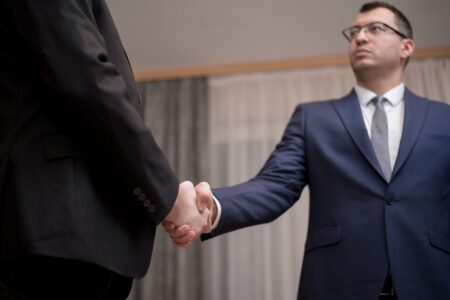 Two professionals shaking hands at a business meeting, representing a private equity acquisition deal