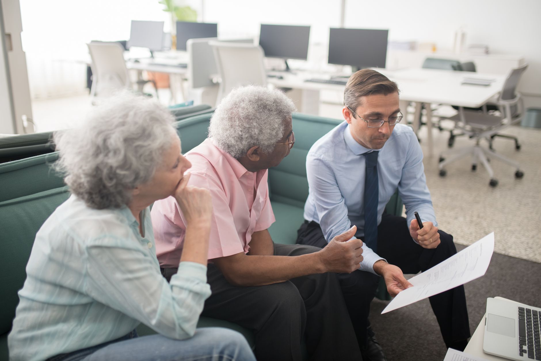 Older couple reviewing financial documents at a desk, planning retirement investments
