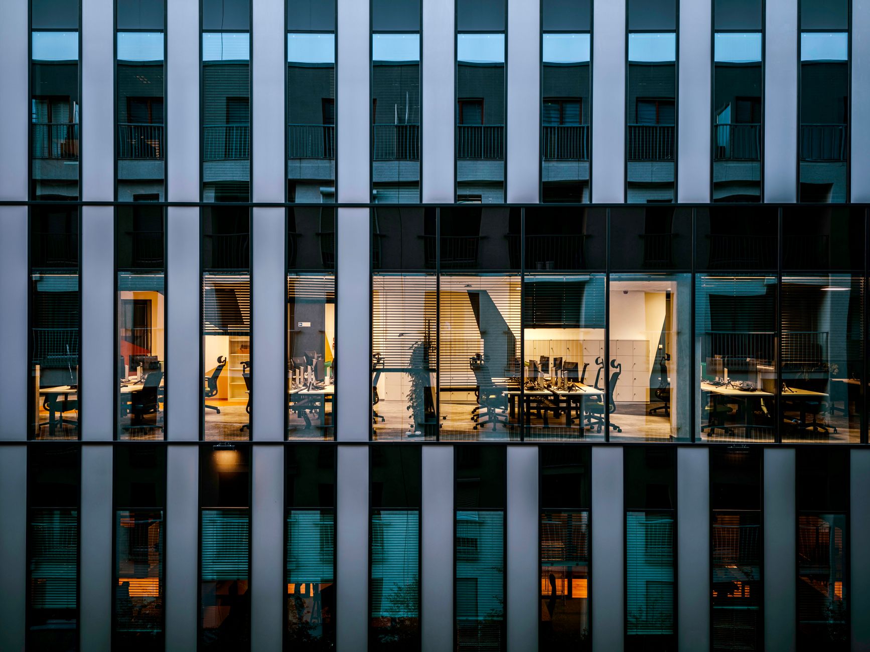 Modern glass office building exterior reflecting city skyline