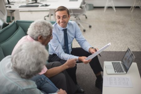 Financial advisor reviewing portfolio documents with a client at a desk