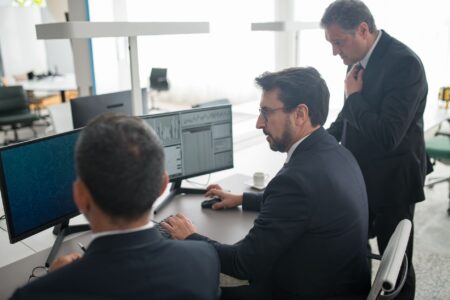 Traders working at a financial desk analyzing bond market data on multiple screens